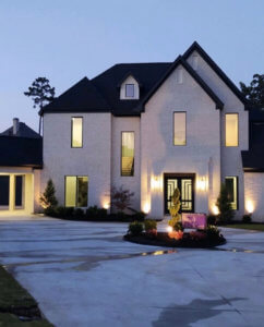 Home exterior with landscape and deck lighting illuminated at dusk